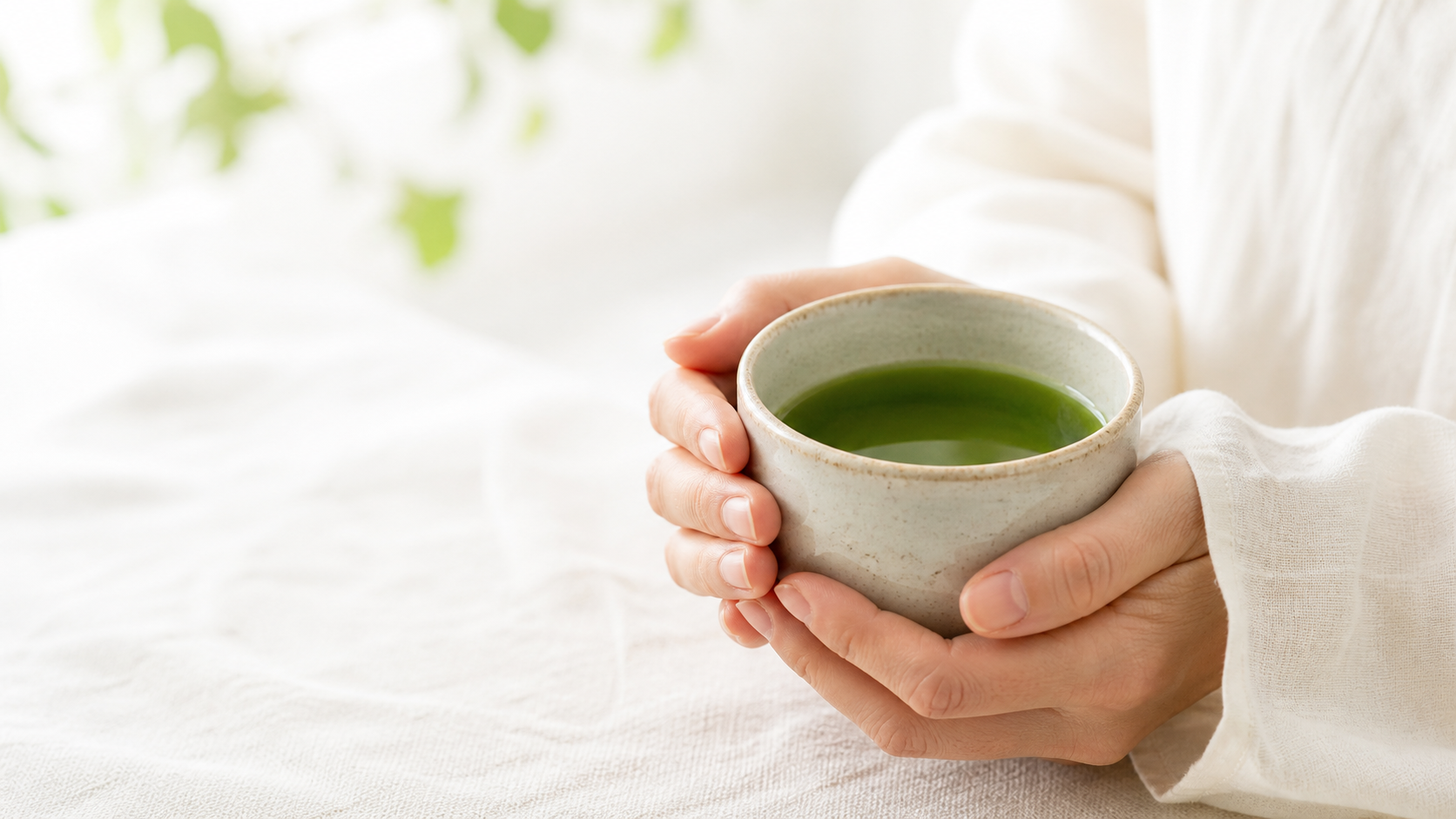 両手で青よもぎ茶の入った湯のみを持つ穏やかな手元